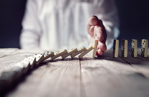 Certificat Conduite du Changement en formation continue Dauphine Executive Education Université Dauphine Paris-PSL en partenariat avec Nexum et Prosci Photo de la main d'un professionnel arretant une suite de dominos symbolisant le Certificat Conduite du Changement en formation continue chez Dauphine Executive Education en partenariat avec Nexum et Prosci