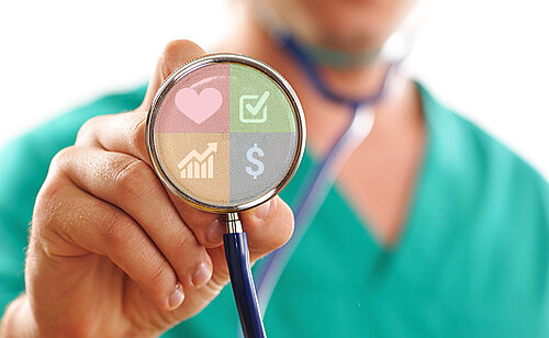 Médecin en blouse verte avec un stéthoscope montrant des pictogrammes liés à la value based healthcare. Conférence La Value Based HealthCare (VBHC) ou du bon usage des indicateurs, Executive MBA Santé Dauphine-PSL