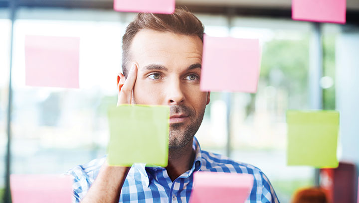 Photographie d'un homme travaillant sur un projet avec des post-it représentant Les hypothèses : un outil clé des approches test & learn  - Certificat Accompagnateur Startup Projet Intrapreneuriat - Dauphine Executive Education et Epigo  